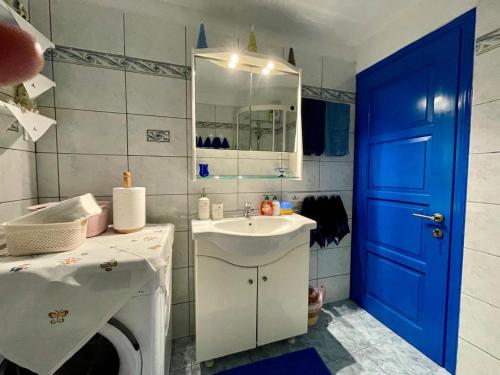 a bathroom with a sink and a blue door at Cycladic House with Aegean Sea View in Aegiali