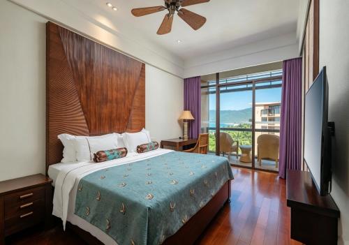 a bedroom with a bed and a television and a balcony at Yalong Bay Mangrove Tree Resort in Sanya