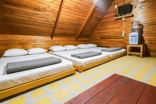 two beds in a room with wooden walls at Cozzy Villa TB & Outbond in Riunggunung