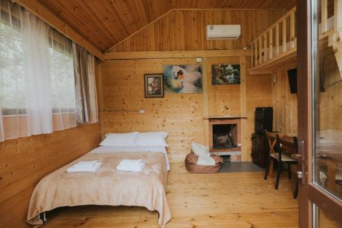 a bedroom with a bed in a wooden house at River Land Cottages in Tsʼkhmorisi