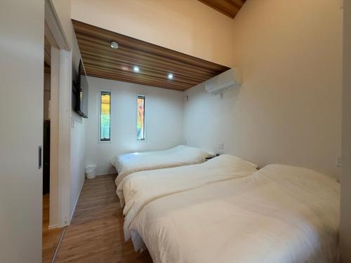 two beds in a room with white walls and wood floors at テラスKawazu in Kawazu