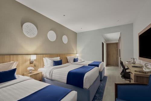 a hotel room with two beds and a desk at Makarem Umm Al Qura Hotel in Mecca