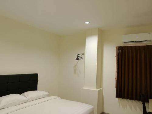 a bedroom with a bed with white sheets and a window at Priority Teuku Umar Samarinda in Loa Bakong