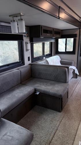 a living room in an rv with a couch and windows at كرفان نور القمر in Al Namas