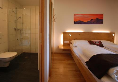 a bedroom with a bed and a shower and a toilet at EdelWeiss AlpinLodge in Matrei in Osttirol
