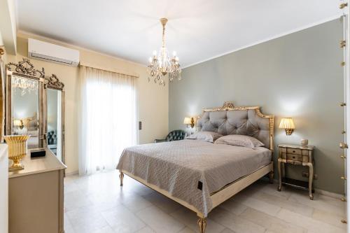 a bedroom with a large bed and a chandelier at Mythodea Luxury Villa Ι Sunset Horizon & Jacuzzi in Naxos Chora
