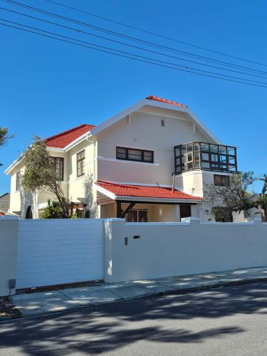 a white fence in front of a white house at Open plan apartment in Muizenberg in Muizenberg
