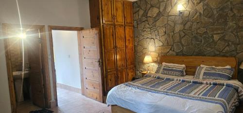 a bedroom with a bed and a stone wall at Green's Cottage in Nathia Gali