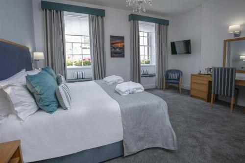 a bedroom with a large white bed with blue pillows at Best Western Moores Central Hotel in St. Peter Port