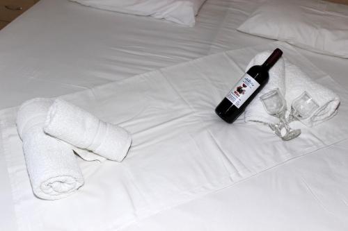 a bottle of wine and two glasses on a bed at Angela Apartments in Kavos