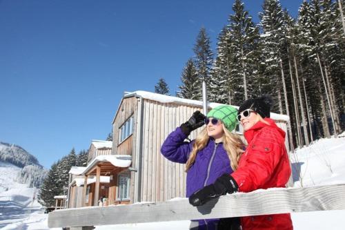 two women standing on a fence in the snow at Hüttendorf Präbichl 1 in Vordernberg