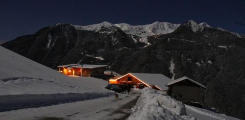 a cabin in the snow at night with a mountain at Schauinstal Appartement 2 in Lutago
