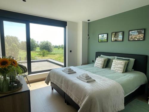 a bedroom with a large bed and a large window at Villa Flandre in Berlare