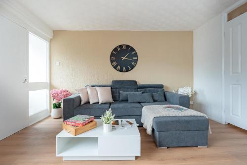 a living room with a blue couch and a clock at Open Mind Property - 3BR with Free Parking & Garden in Portsmouth