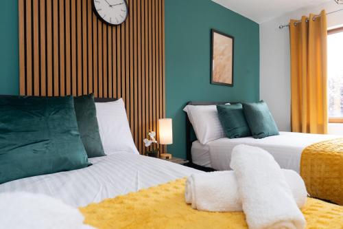 a bedroom with two beds and a clock on the wall at Open Mind Property - 3BR with Free Parking & Garden in Portsmouth