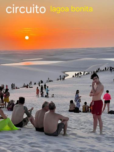 a group of people sitting on the beach at sunset at Pousada Recanto Sapoti in Barreirinhas