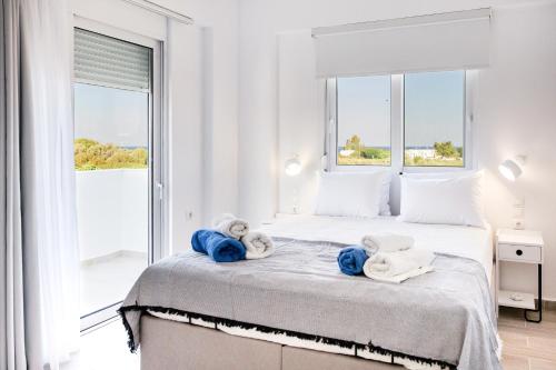 a white bedroom with two beds with towels on them at NEP APT Gennadi in Gennadi