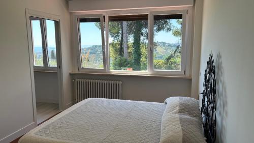 a bedroom with a bed and two large windows at Brezza sul Colle in Montesilvano