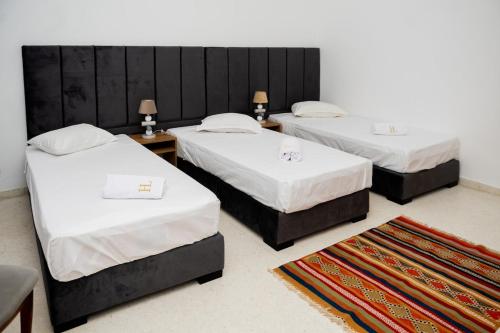 two beds in a room with two tables at VILLA Lafayette in Tunis