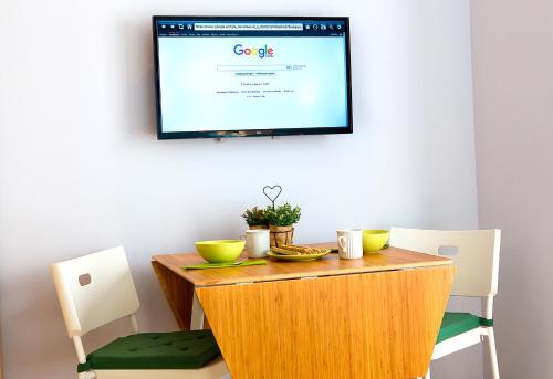 einen Tisch mit 2 Stühlen und einen TV an der Wand in der Unterkunft Emerald Suite in Athen