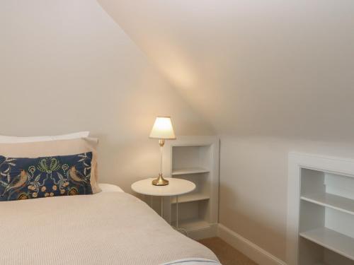 a bedroom with a bed and a table with a lamp at Keepers Cottage in Haddington