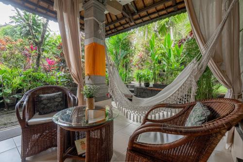 a porch with a hammock and a table and chairs at Pondok Alami Villas 5BR & Pool in Ubud