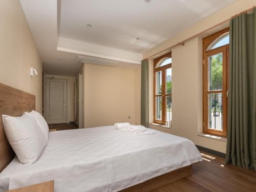 a bedroom with a large white bed with windows at The Mint Urla in Kuscular