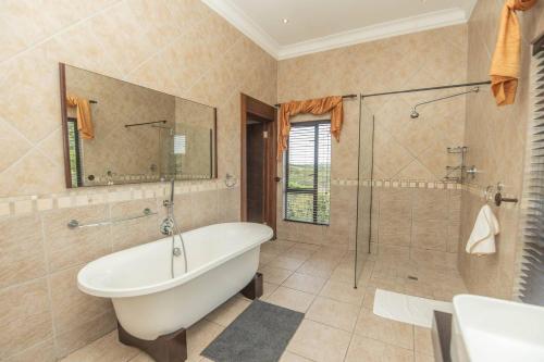 a bathroom with a tub and a shower and a sink at Bevuline in Gqeberha
