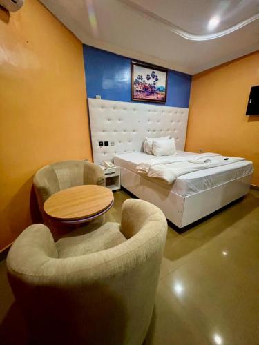 a bedroom with a bed and two chairs and a table at Rotana Hotel and Suits in Ilorin
