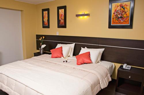 a bedroom with a large white bed with red pillows at Flamante Hotel & Suite in Lima