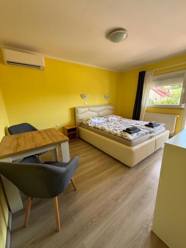 a bedroom with two beds and a desk and a table at AndreaApartmanok in Balatonfüred