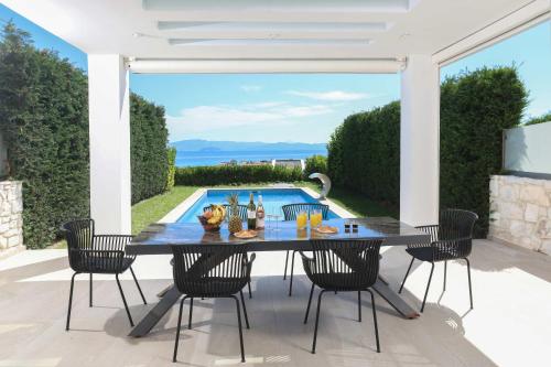 a patio with a table and chairs and a pool at Villa Mare 3 - Private Pool, Sea View in Hanioti