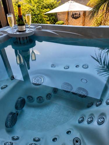 a hot tub with a table and two glasses of wine at 3 Waters Spa - Private Spa with Jacuzzi, Sauna & Hammam in Winenne