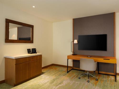 a room with a desk with a television and a chair at Radisson Golf & Convention Center Batam in Batam Center