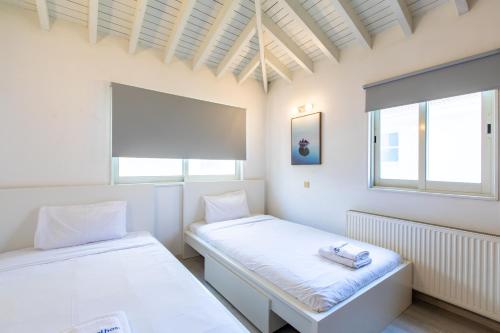 two beds in a room with two windows at Gaia - 4 Bedroom House in Larnaca in Larnaca