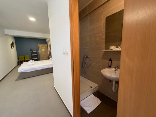 ein Badezimmer mit Waschbecken und ein Bett in einem Zimmer in der Unterkunft Hotel Storia in Čapljina