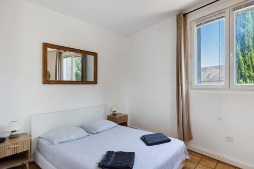 a white bedroom with a bed and a mirror at Studio 5 - 3 min du Futuroscope in Chasseneuil-du-Poitou