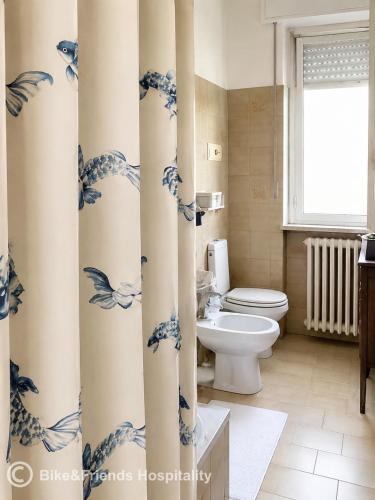a bathroom with a toilet and a blue and white shower curtain at CASA BETTI in Pesaro