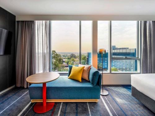 a hotel room with a couch and a large window at Novotel Melbourne Preston in Melbourne