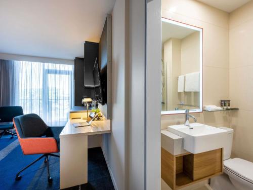 a bathroom with a sink and a toilet and a mirror at Novotel Melbourne Preston in Melbourne