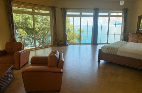 a bedroom with a bed and a couch and chairs at Bord Mer House in Glacis