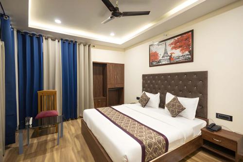 a bedroom with a large bed with blue curtains at Hotel Kamal Palace in Lucknow