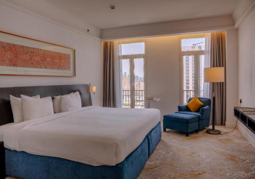 ein Schlafzimmer mit einem großen Bett und einem blauen Stuhl in der Unterkunft K108 Hotel Doha in Doha