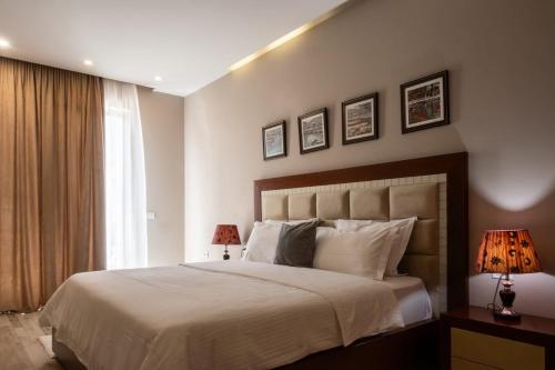 a bedroom with a bed with two lamps and a window at Hotel Magllara in Sarandë