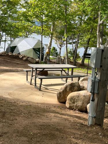 a picnic table with a tent and some rocks at Blue Bayou Dome Village in Dingwall