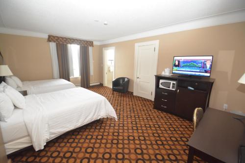 a hotel room with a bed and a flat screen tv at Prince Arthur Waterfront Hotel & Suites in Thunder Bay