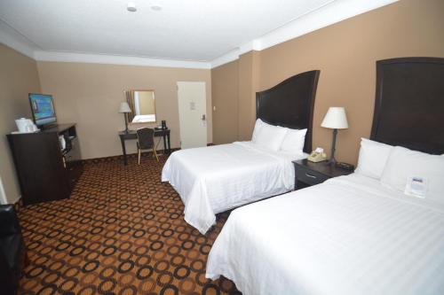 a hotel room with two beds and a desk at Prince Arthur Waterfront Hotel & Suites in Thunder Bay