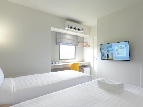 a white room with two beds and a tv on the wall at HOP INN Phetchaburi in Phetchaburi