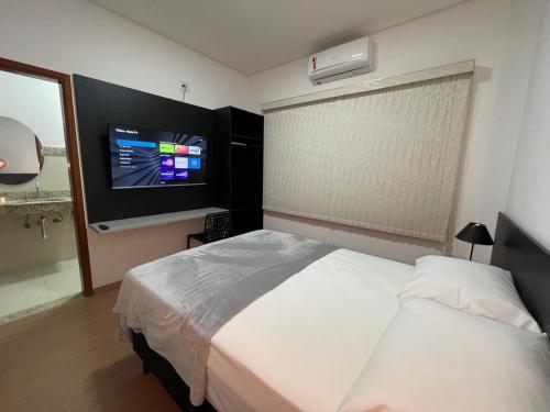 a bedroom with a bed and a flat screen tv at Hotel Valadares in Alfenas