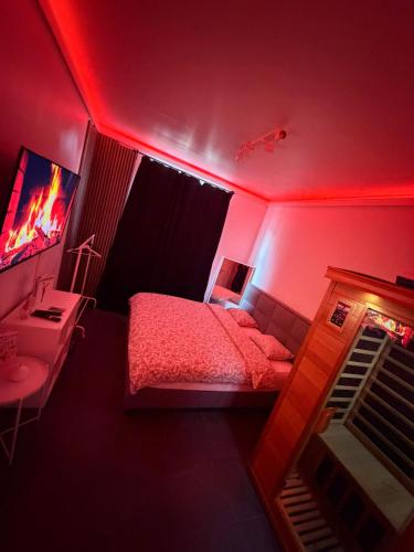 a red room with a bed and a desk and a television at La Suite White wellness Jacuzzi & Sauna in Seraing
